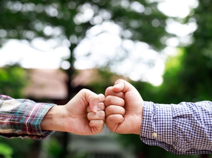 Business owner fist bumping with web designer representing trusted website care partnership